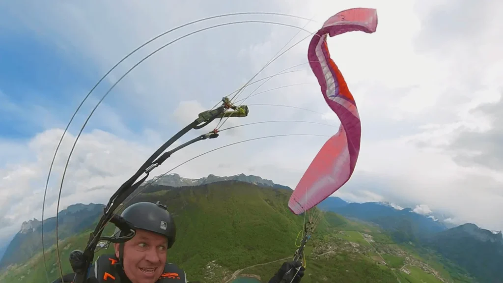 A paraglider pilot on SIV training looks at his wing which is bent over his head at a worrying angle