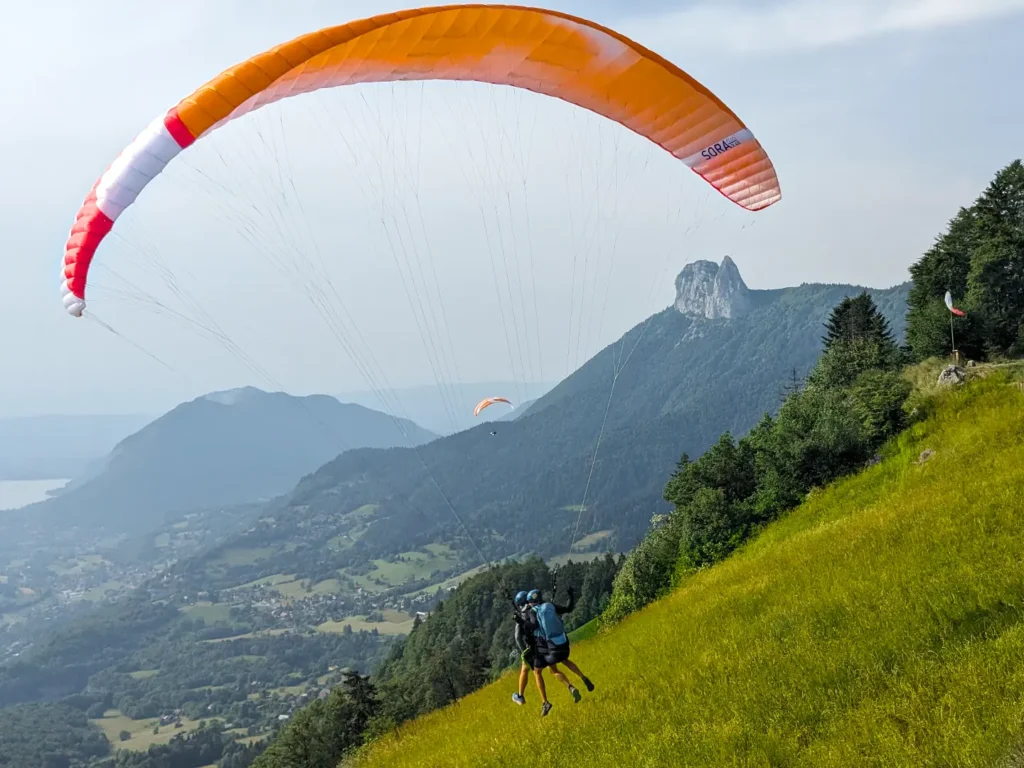Pilote et passager sous une aile de parapente décolle en s'envolant naturalement du col de la Forclaz